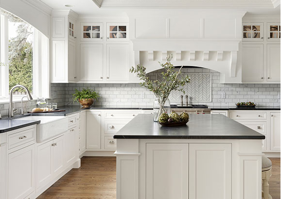 Traditional kitchen remodel with white cabinets, custom range hood, and black countertops