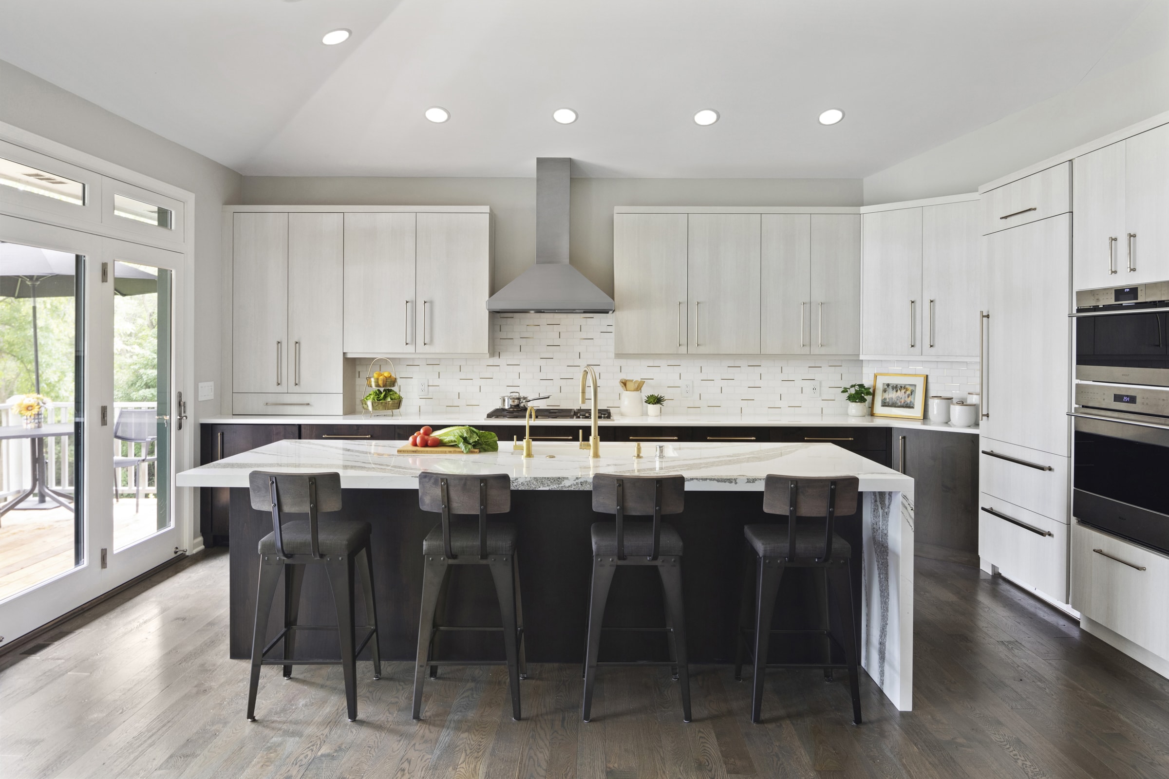 Kitchen remodel with dark base cabinets, white upper cabinets, and  waterfall island