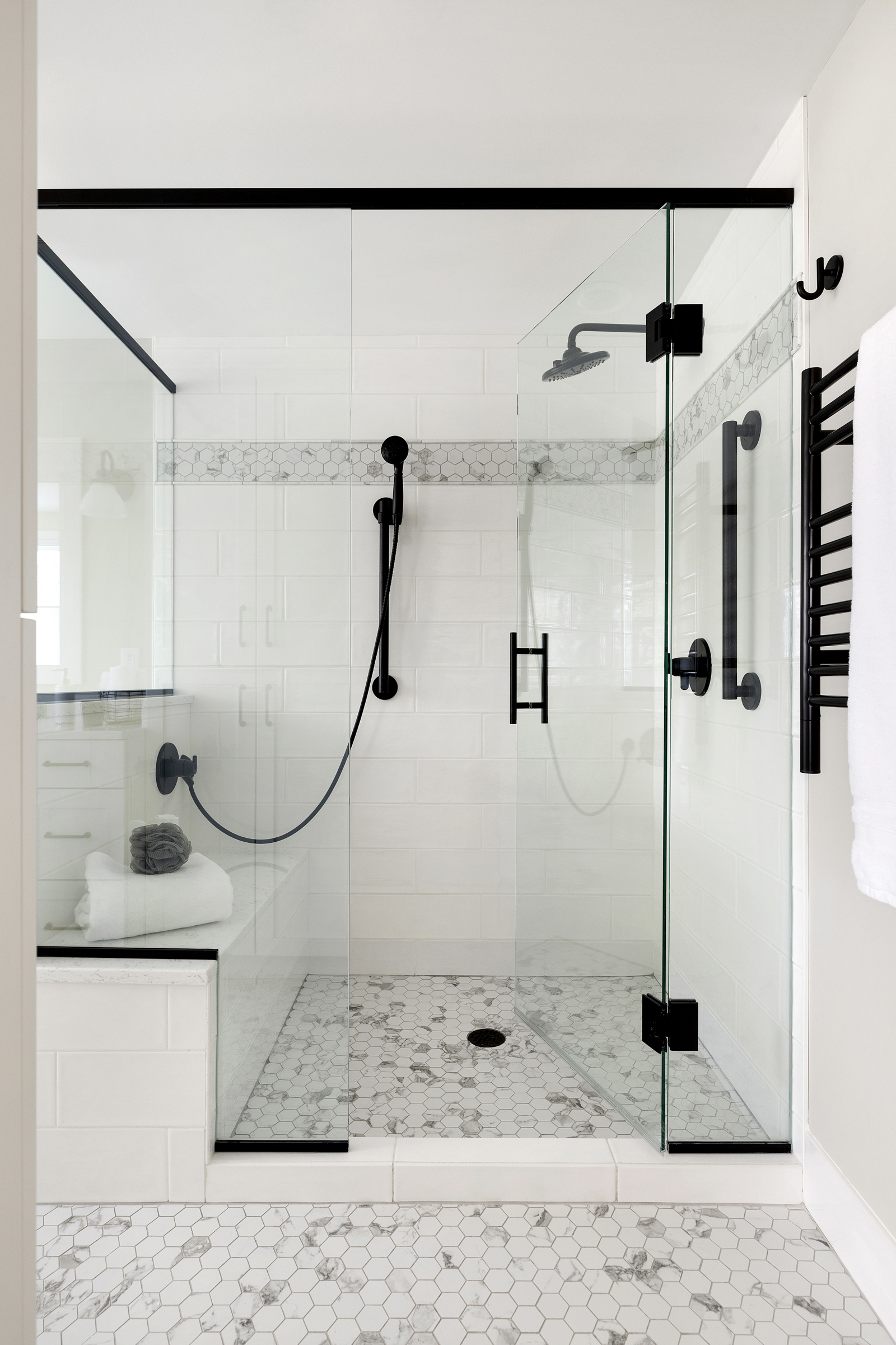 Bathroom renovation with walk in, glass enclosed shower with white marble tile, and black fixtures
