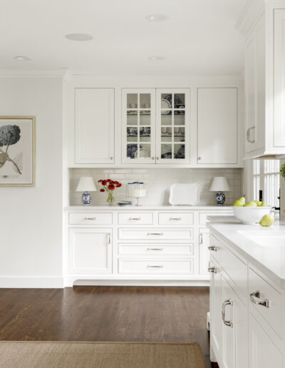 Kitchen remodel with white cabinets and wood floor. Glass upper cabinet to showcase dishware