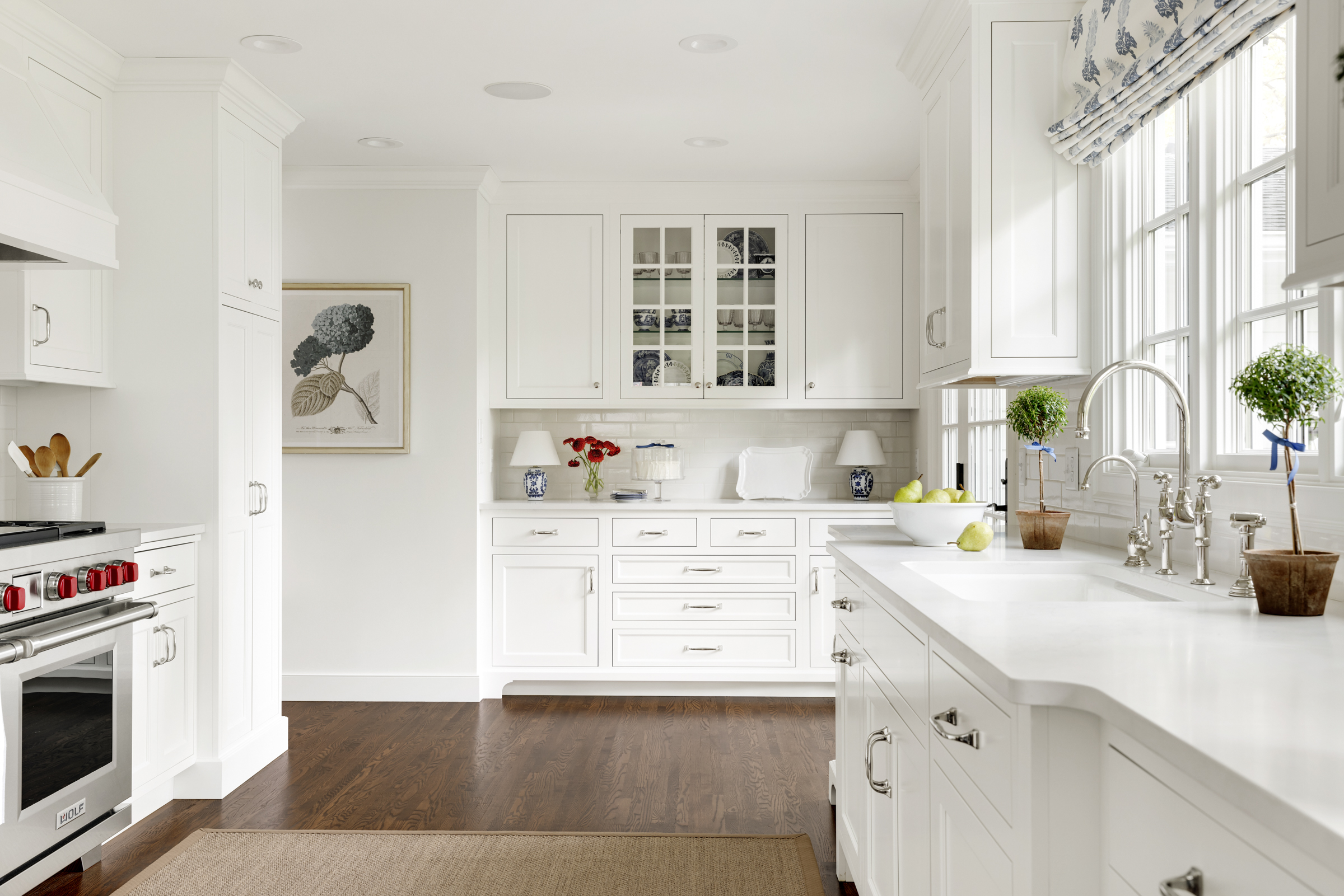 Kitchen remodel with white cabinets and wood floor. Glass upper cabinet to showcase dishware