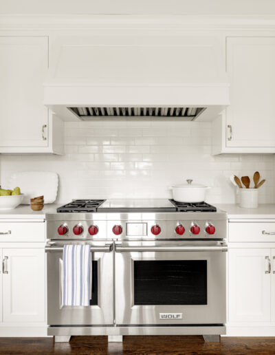 Kitchen remodel with white tall pantry cabinets and Wolf range and custom white hood