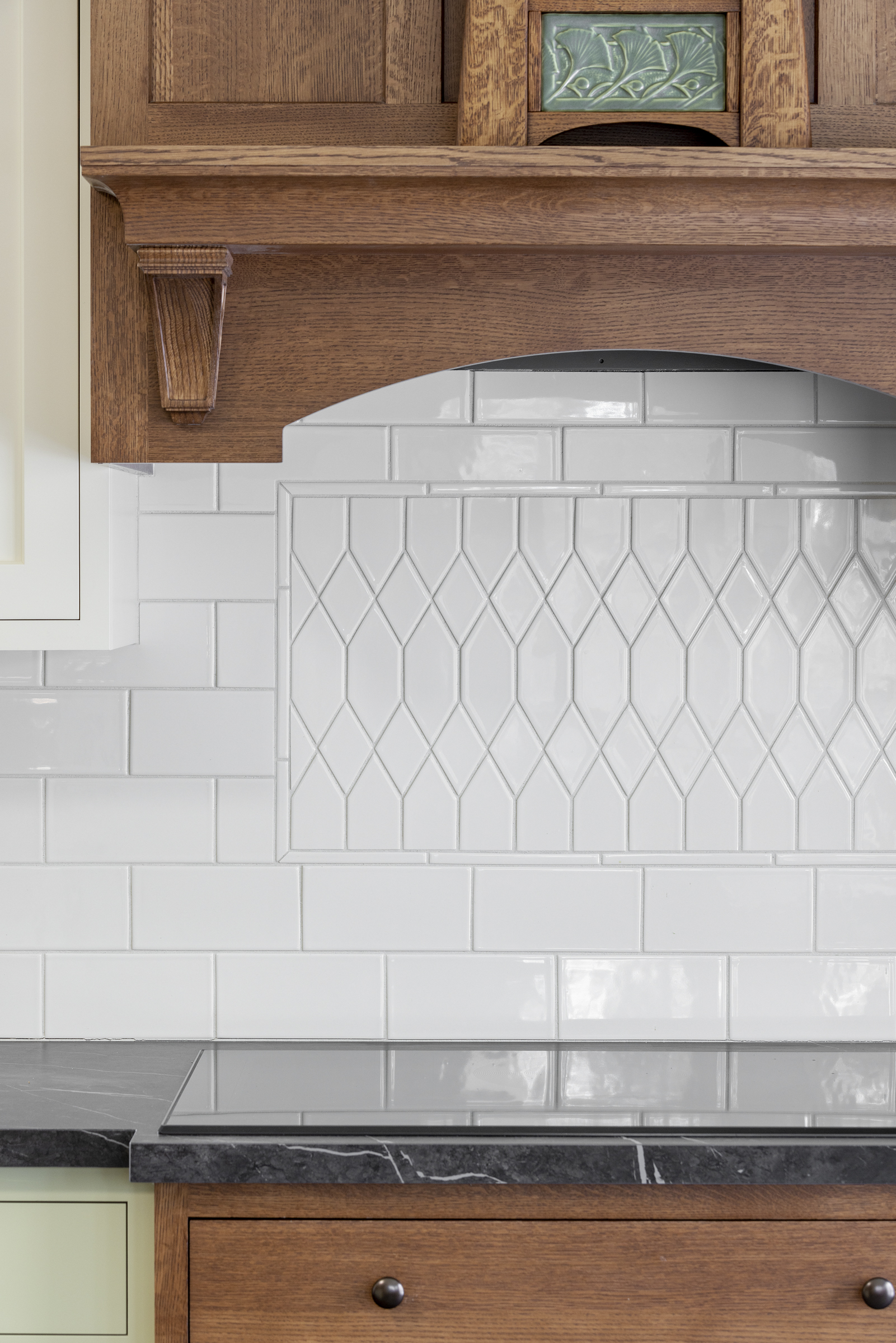 Kitchen remodel with white tile backsplash above stove top with custom wooden hood vent