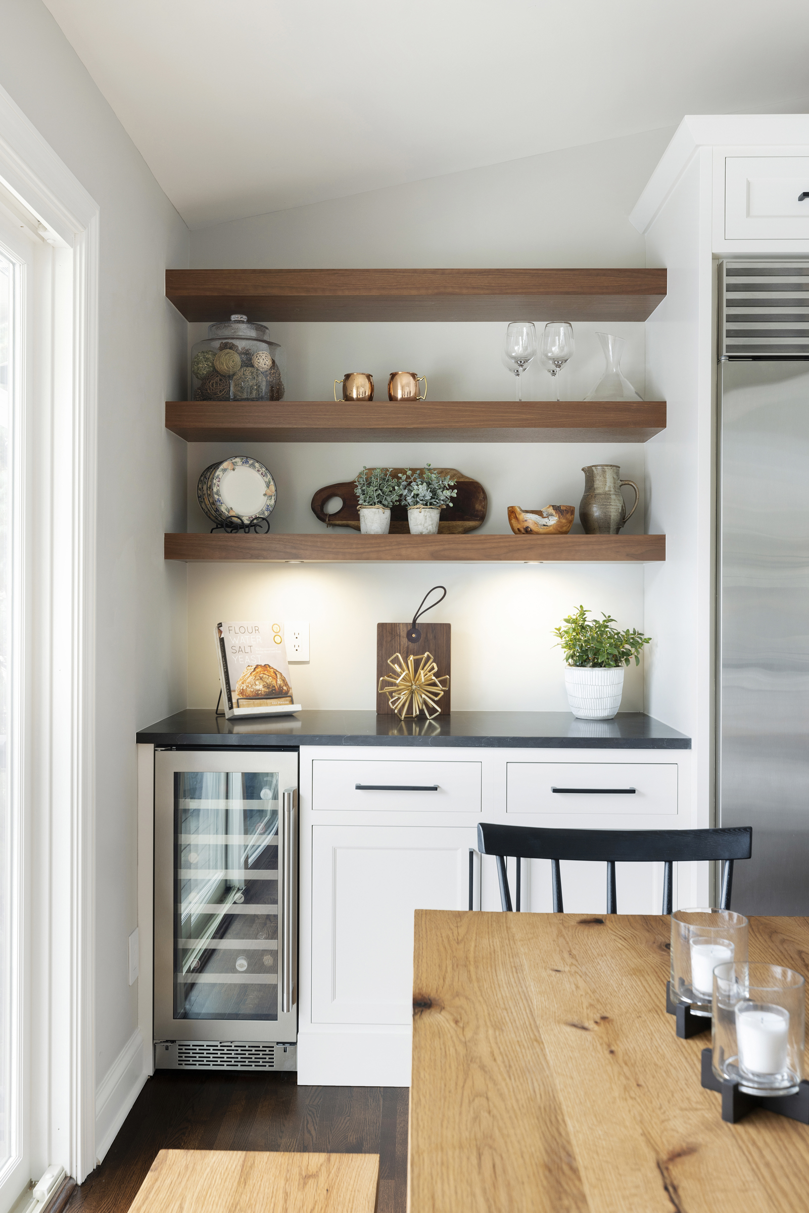 Kitchen with wooden floating shelf and white base cabinets