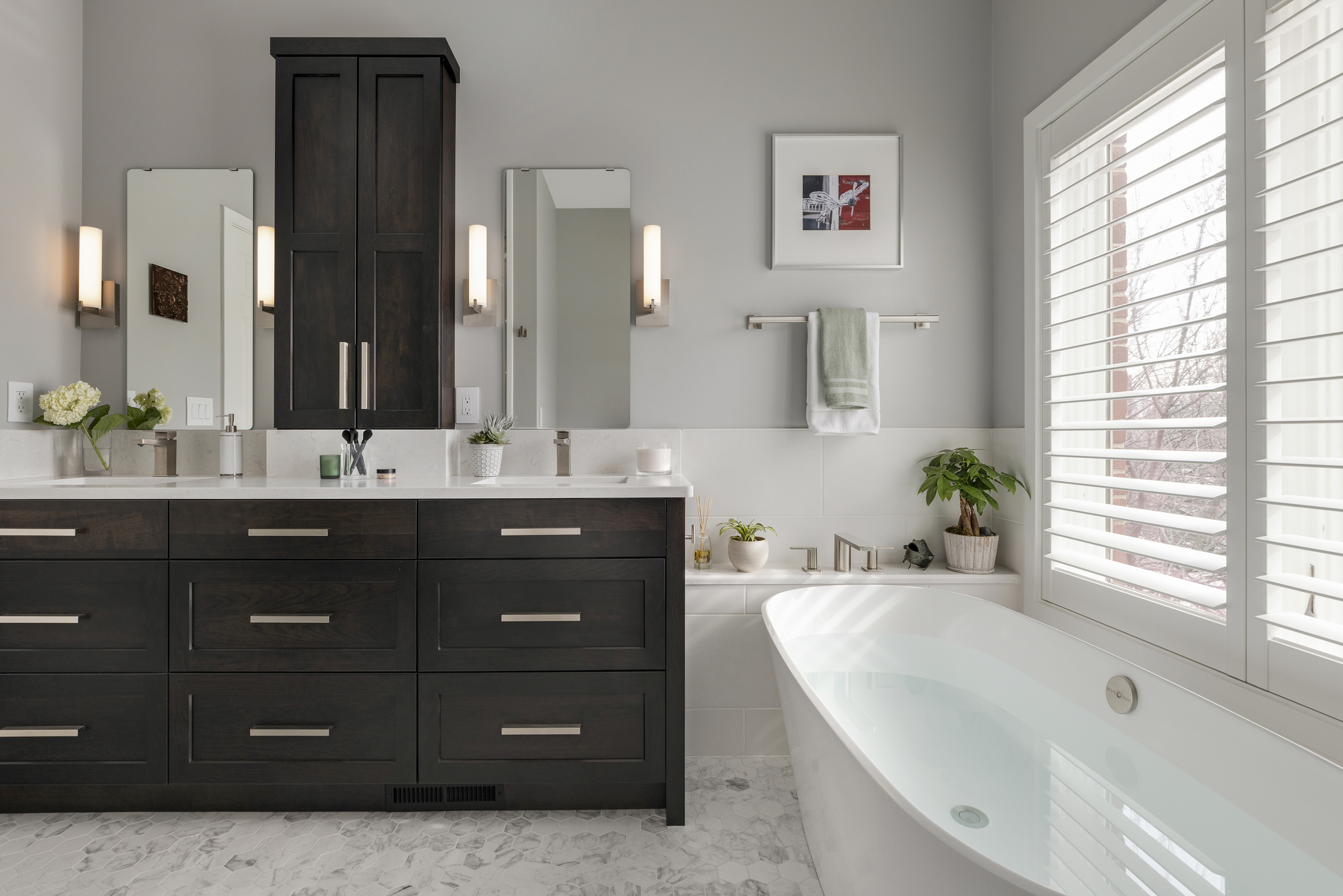 Primary bathroom remodel with large soaker tub under windows and dark wood vanity with double sinks and mirrors