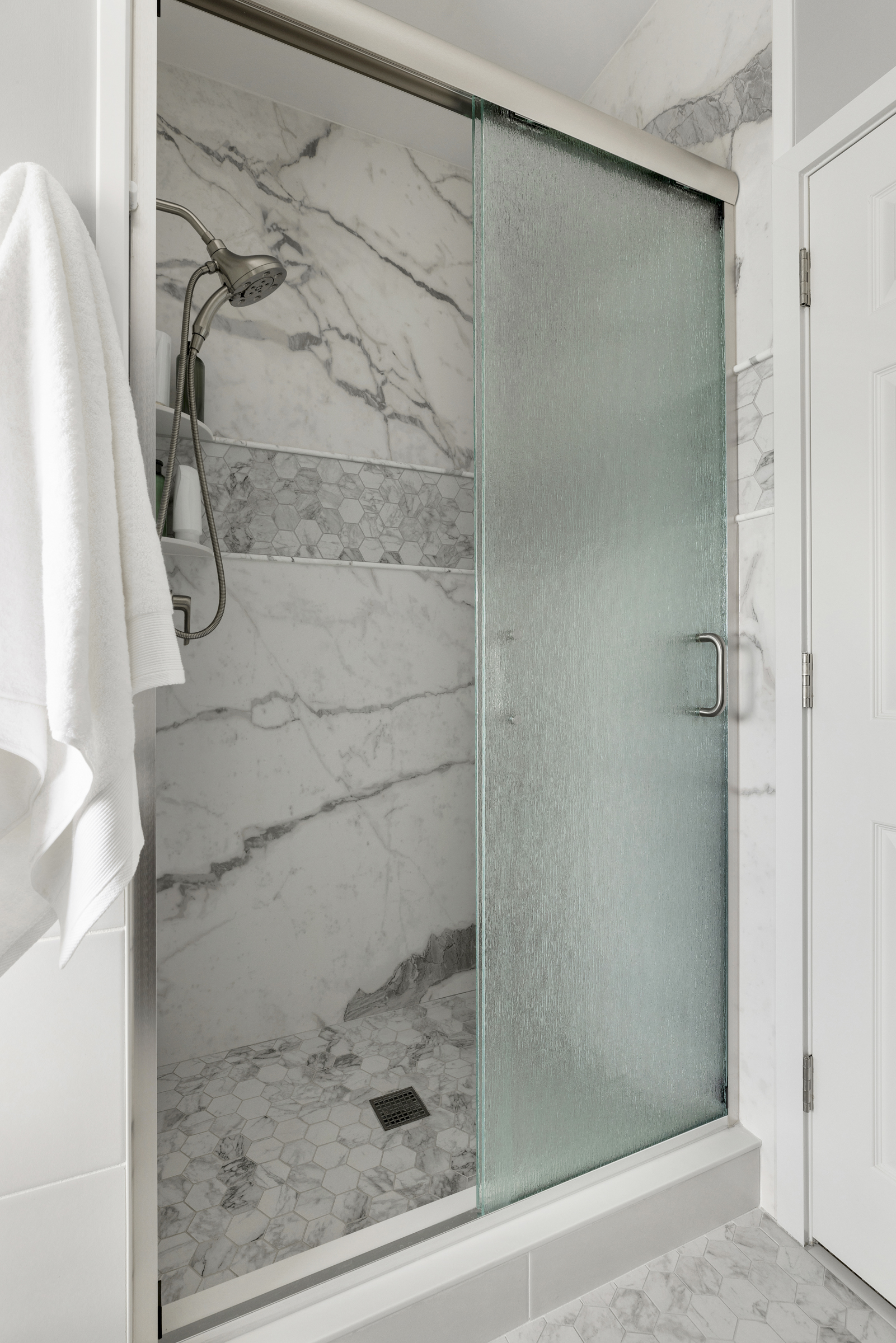 Bathroom remodel with large walk in shower with marble walls and frosted call panel