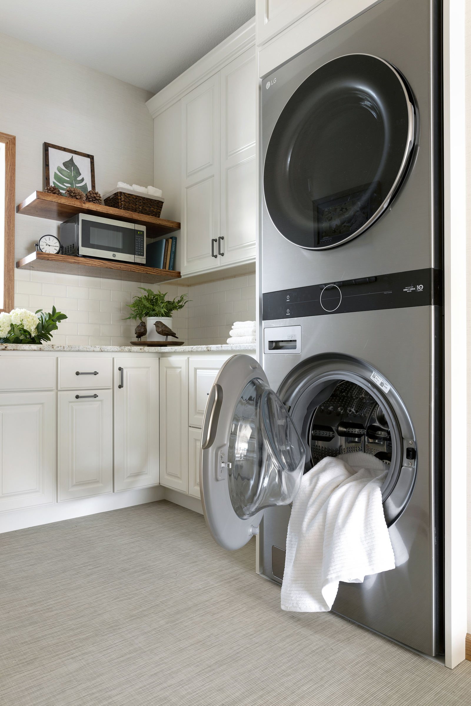 Laundry room remodel with stacked washer and dryer and white cabinets