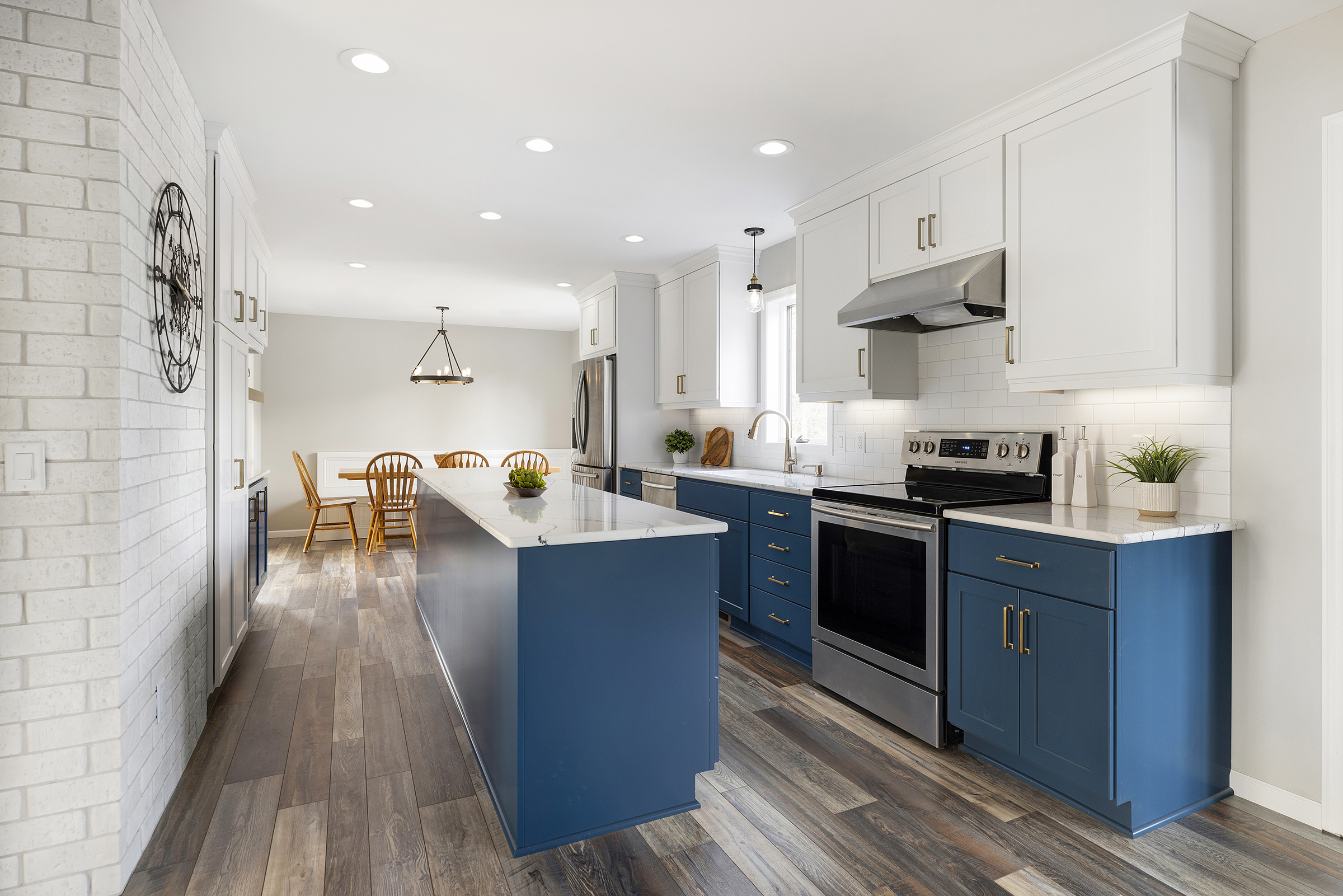 Remodeled kitchen with blue base cabinets, white upper cabinets, brick wall, and eat in dining area