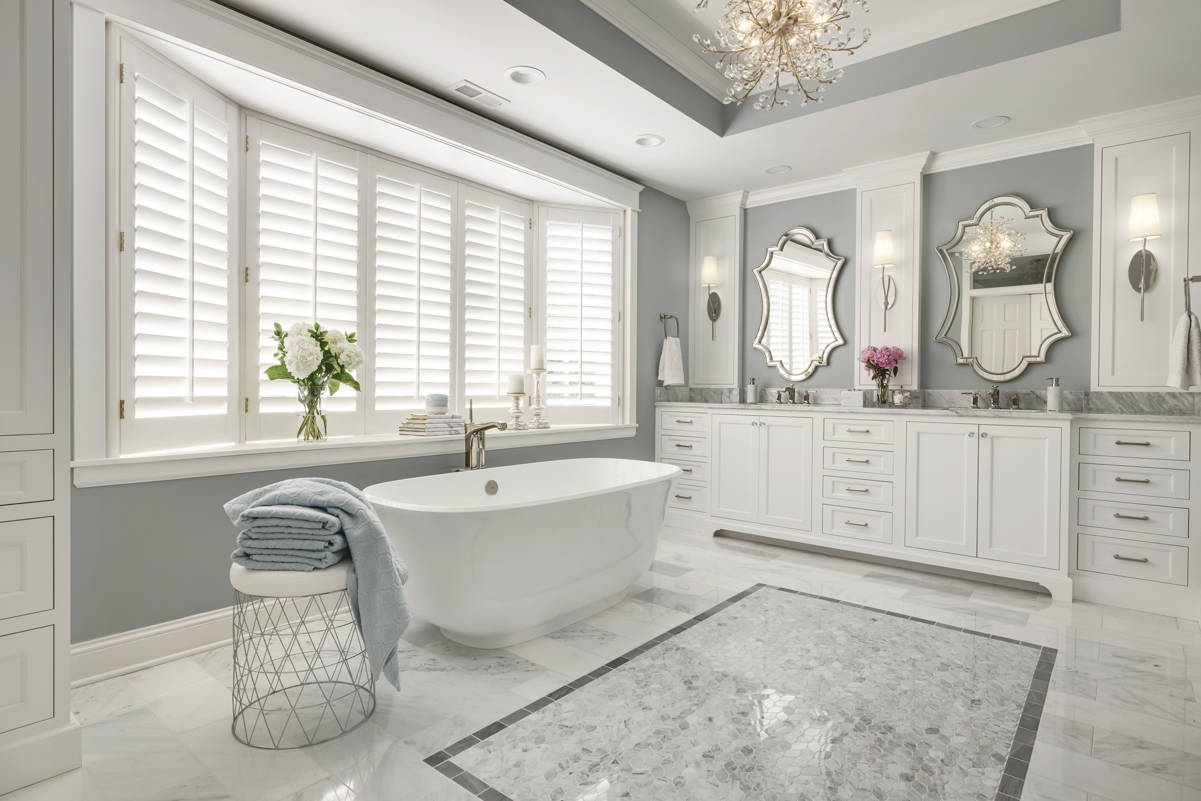 Primary bathroom with marble floor tile, large soaker tub, double vanity, and chrome details
