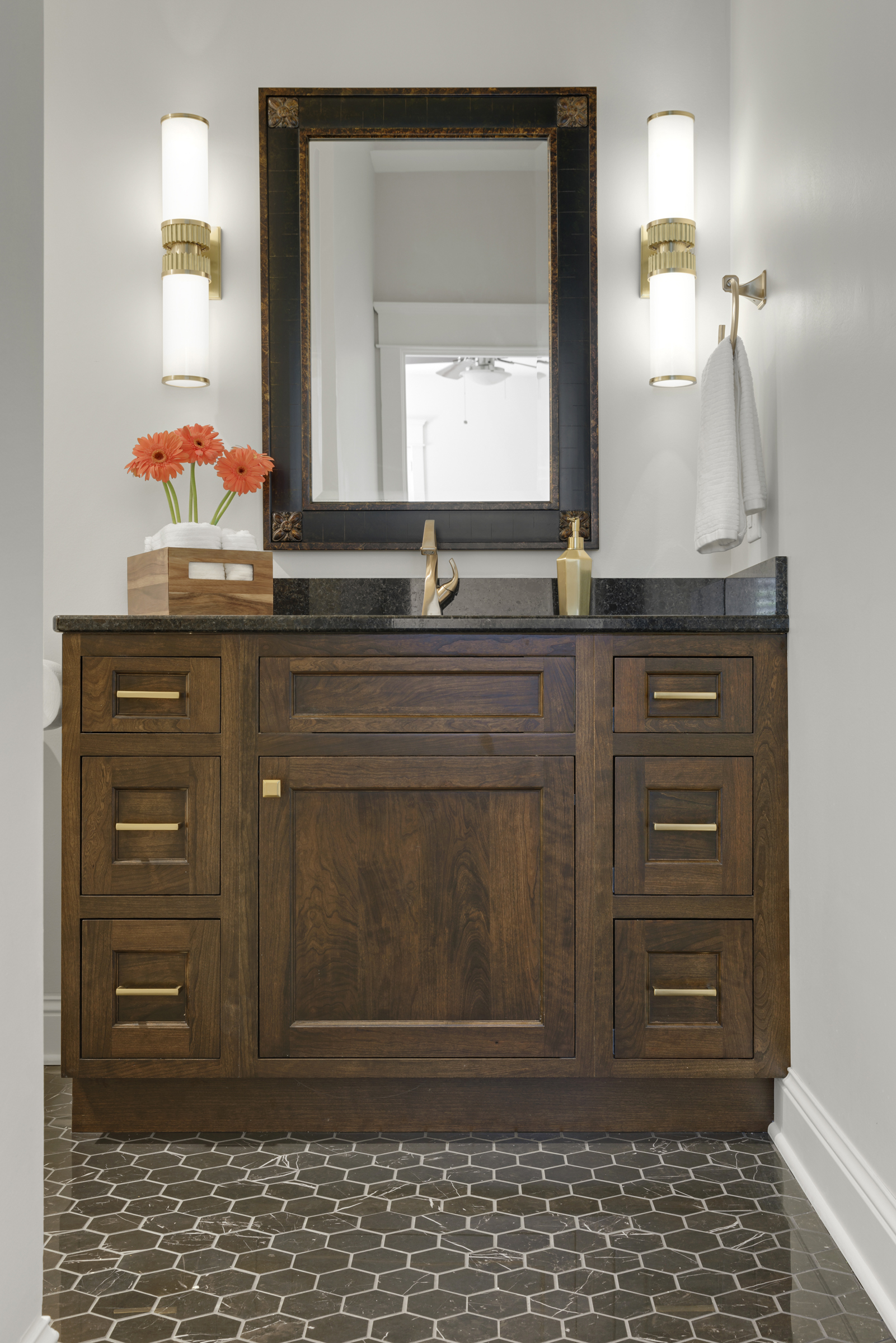 Guest Bathroom remodel with dark hexagon floor tile, wooden vanity, and gold fixtures