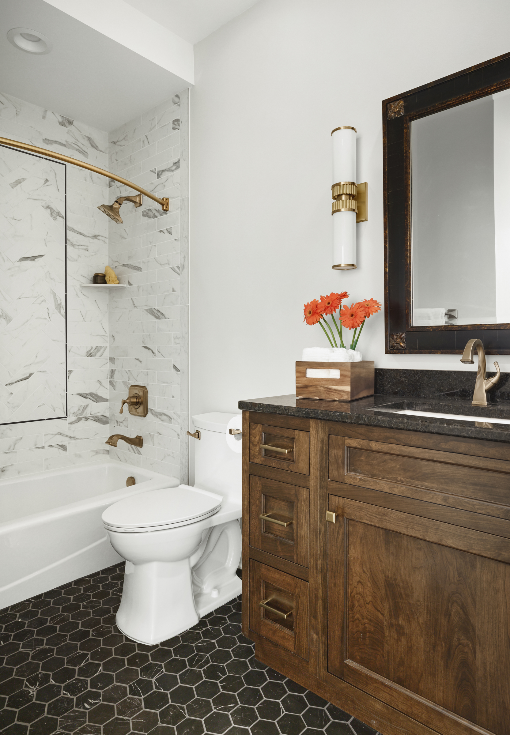 Guest Bathroom remodel with dark hexagon floor tile, wooden vanity, and gold fixtures