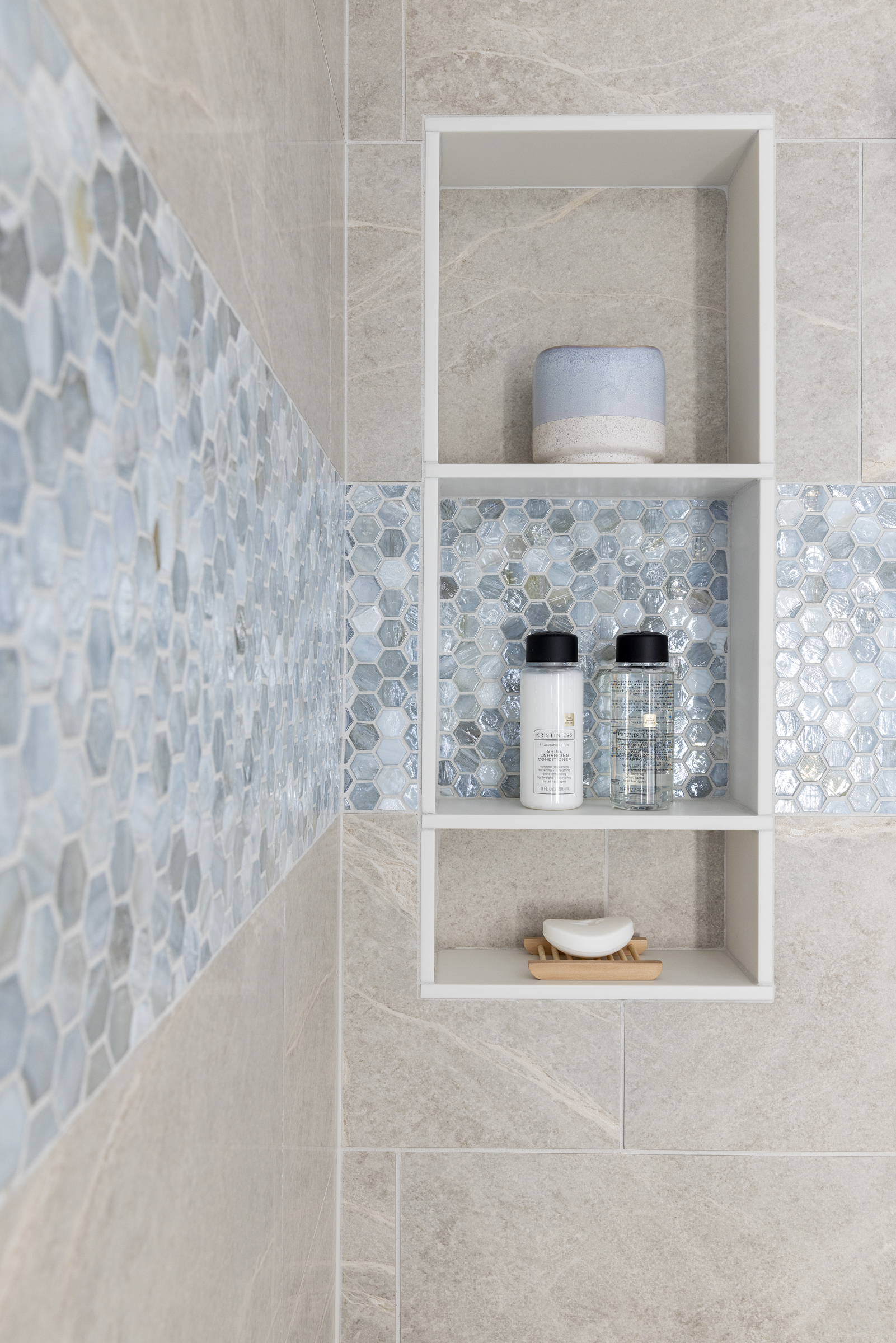 Primary bathroom remodel with shower with tan tile and blue accent tile around shower and built in shelves for shampoo and soap