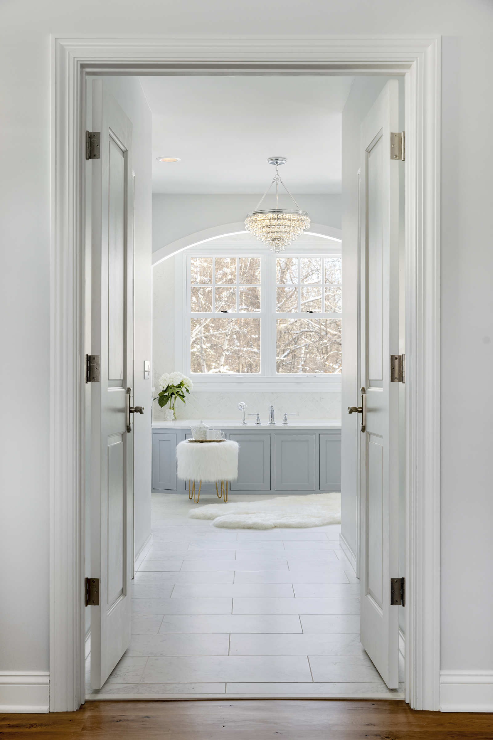 European inspired bathroom remodel with light blue vanity and white tile floor