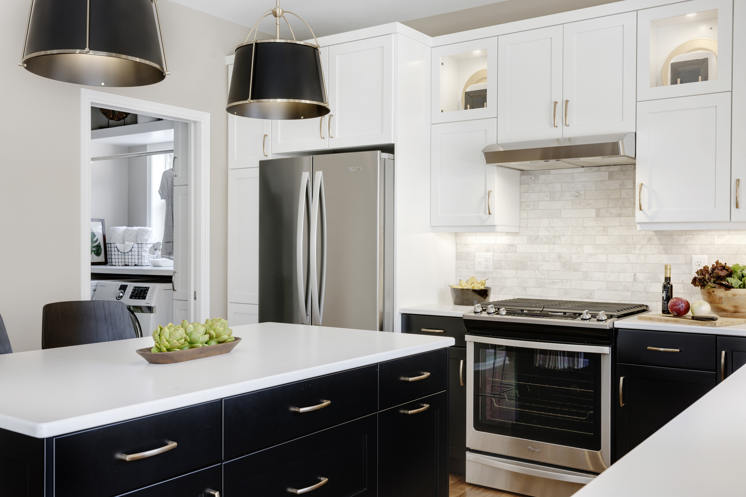 Bold kitchen renovation with black base cabinets, white upper cabinets, wood floor, and large island