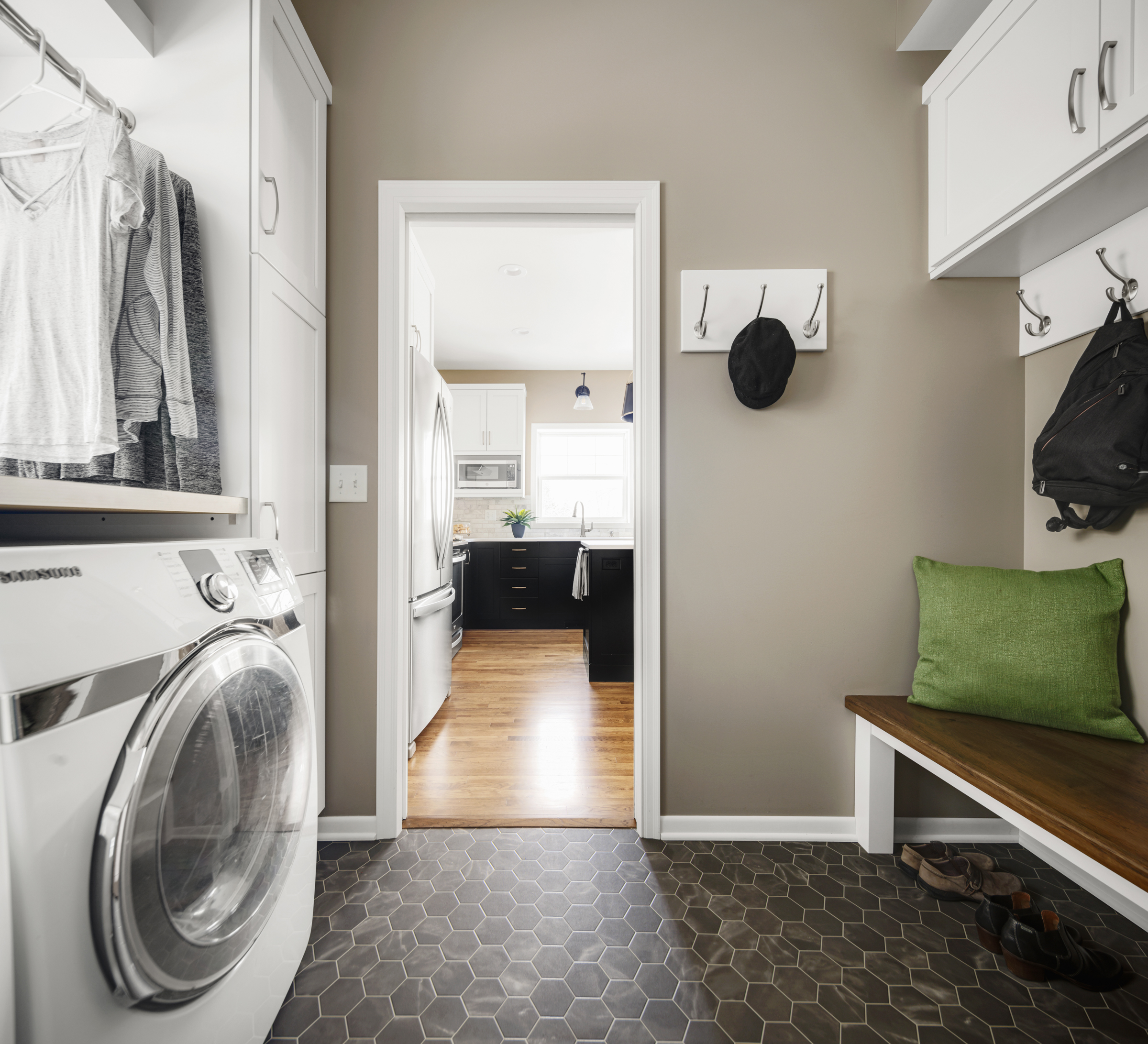 Bold laundry room renovation with dark tile floors, tan walls, and white cabinets