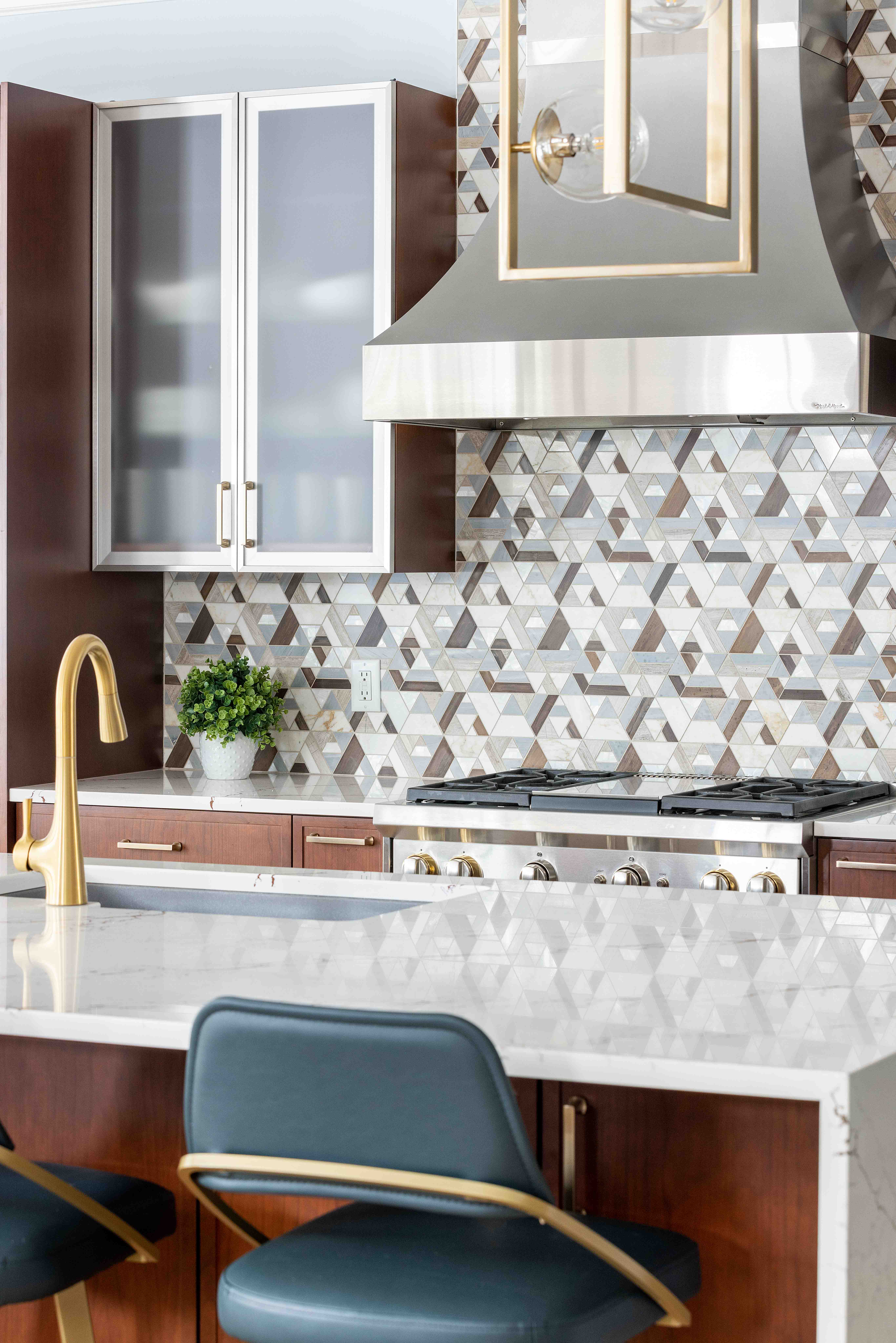 Kitchen remodel with patterned tile backsplash, blue leather bar stools, and mixed metal fixtures