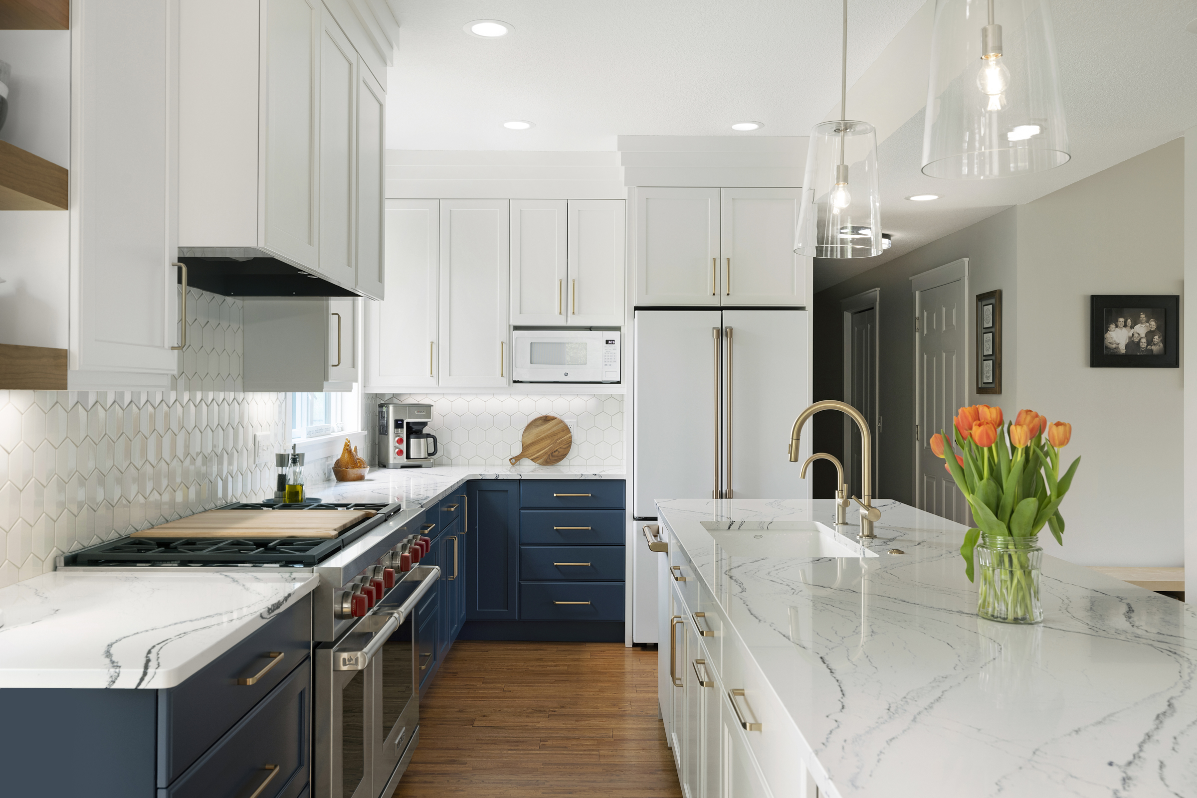 Kitchen remodel with large island with pendant lights, blue cabinets, and wood floors