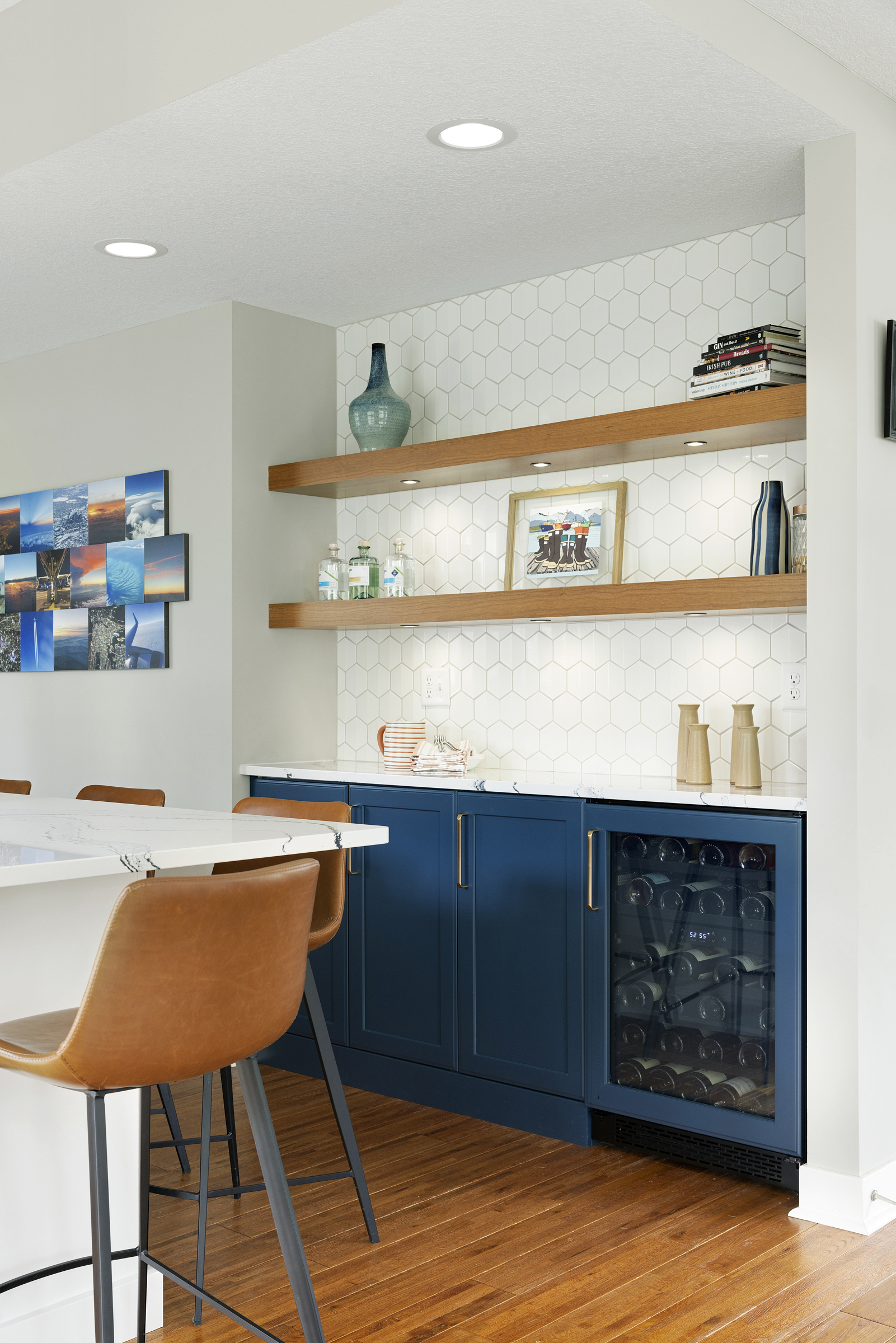Kitchen remodel with blue base cabinets with built in wine fridge and floating wood shelves above