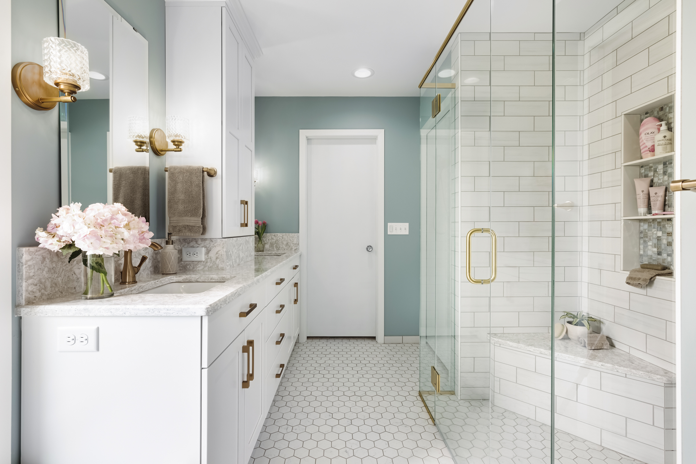 Bright primary bathroom remodel with blue accent wall, large walk-in shower, and gold metal