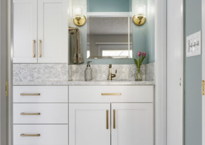 Bright primary bathroom remodel with blue accent wall, large walk-in shower, and gold metal