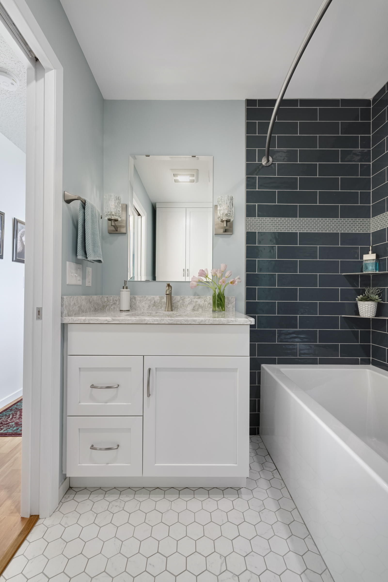 spacious hall bathroom with shower and bathtub with blue wall tiles and white cabinet