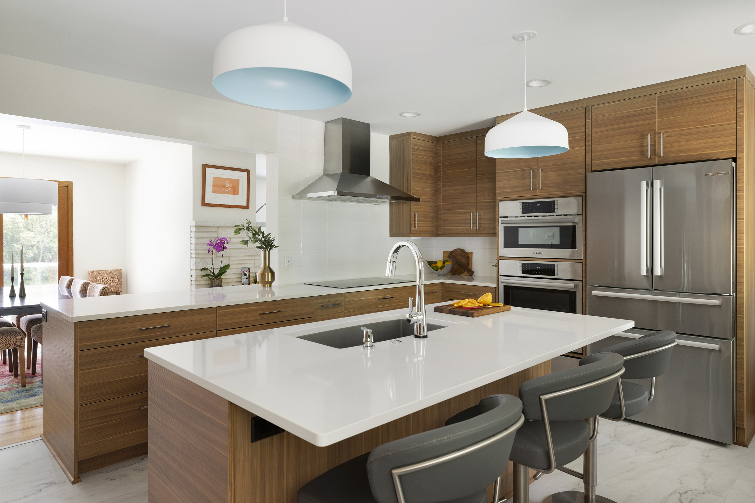 Modern kitchen remodel with medium toned wood cabinets, white countertops, and stainless steel appliances