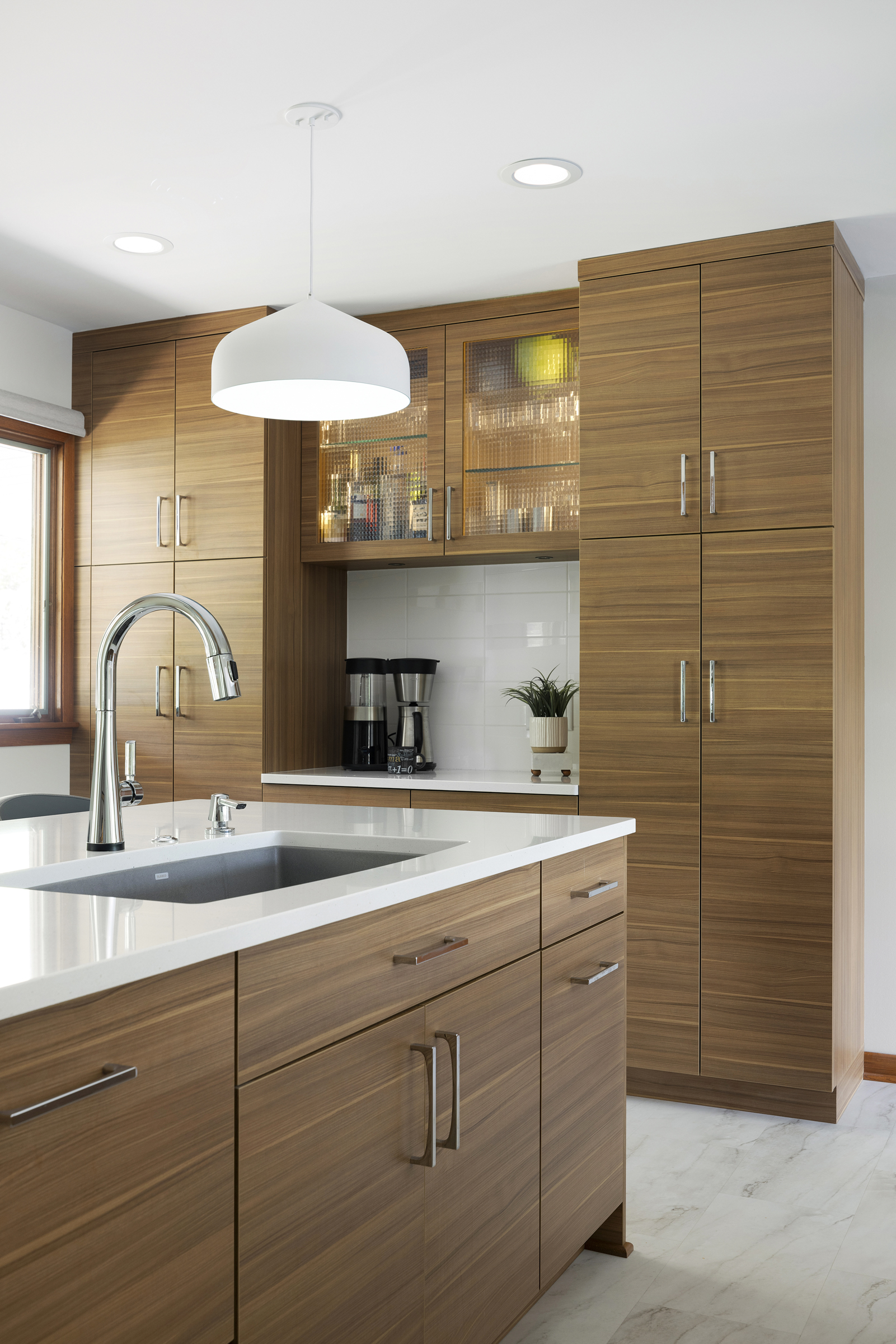 Modern kitchen remodel with medium toned wood cabinets, white countertops, and stainless steel appliances