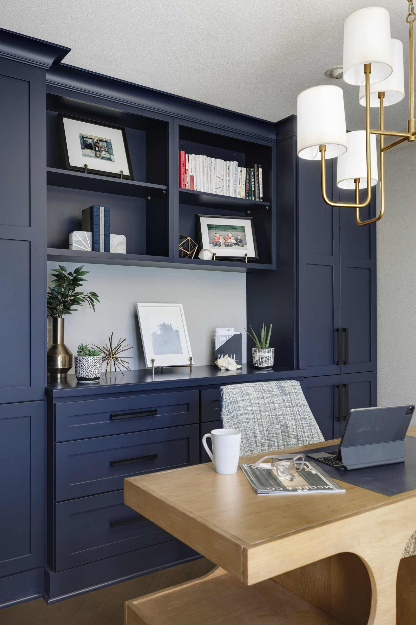 Contemporary home office with dark blue built in storage behind light wood desk