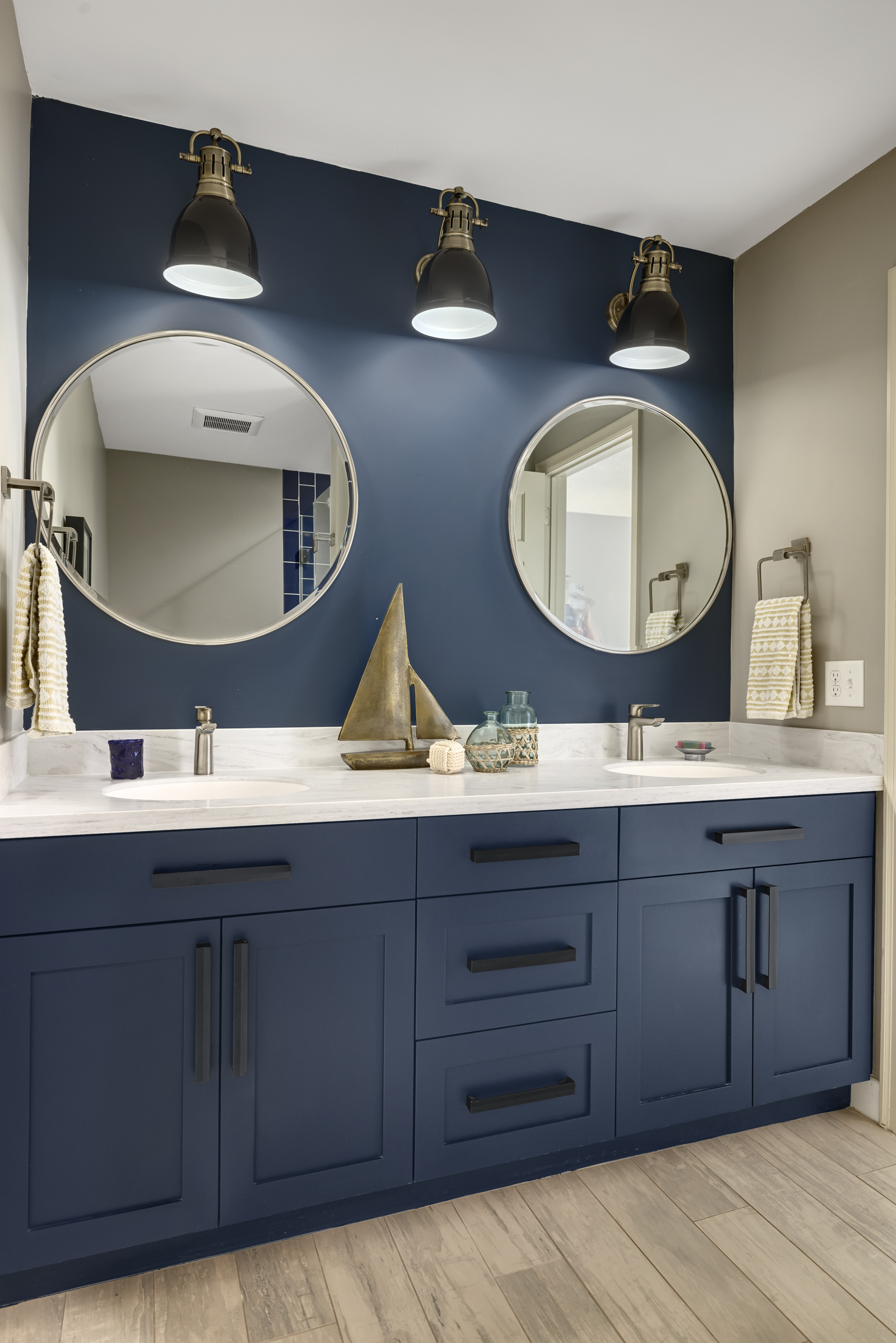 Bathroom remodel with blue cabinet and round mirrors above sinks