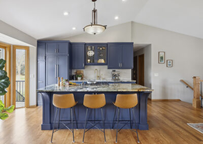 Kitchen remodel with blue cabinets, medium toned wood floor, and open floor plan