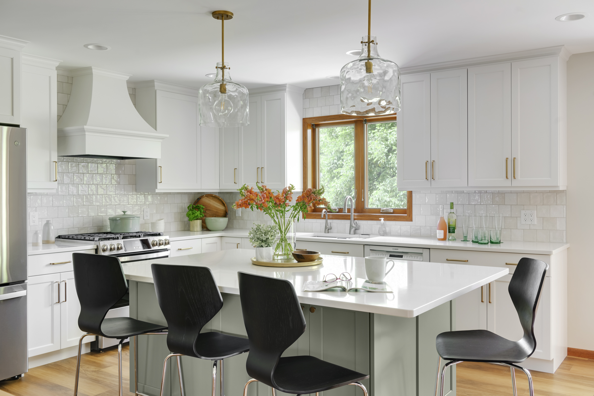 Kitchen remodel with warm wood floors, light green island, and white cabinets