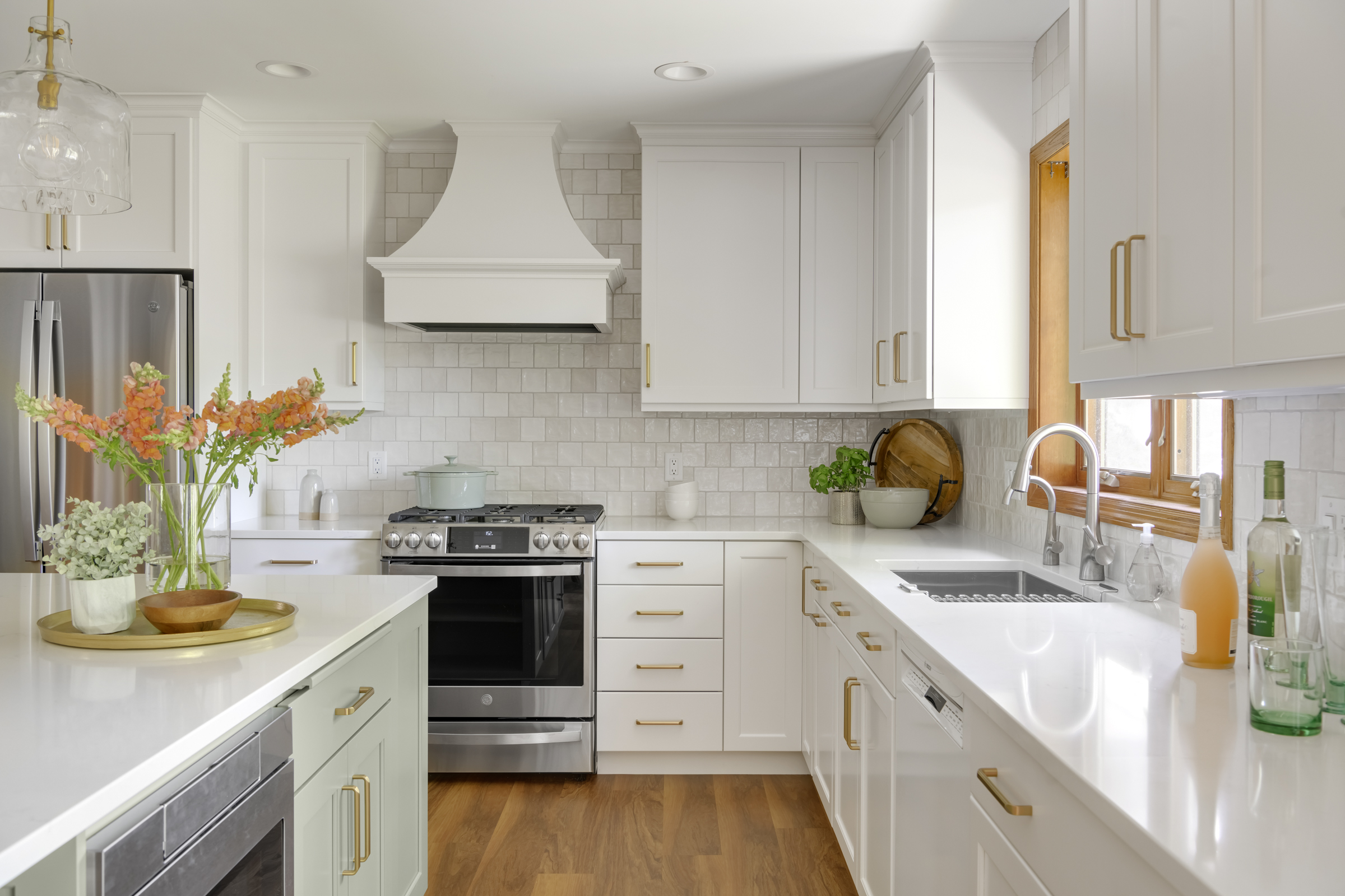 Kitchen remodel with warm wood floors, light green island, and white cabinets