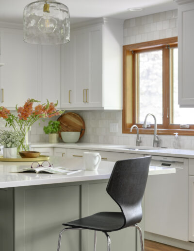 Kitchen remodel with warm wood floors, light green island, and white cabinets