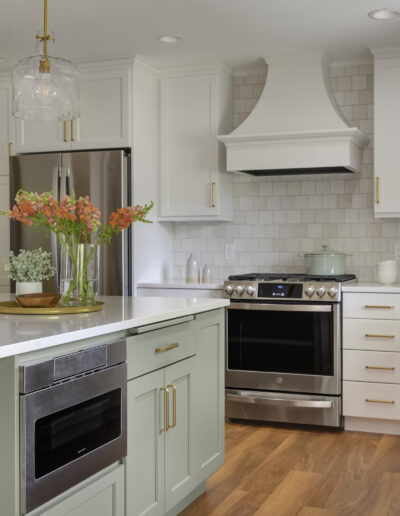 Kitchen remodel with warm wood floors, light green island, and white cabinets