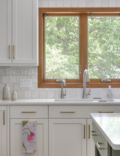 Kitchen remodel with warm wood floors, light green island, and white cabinets